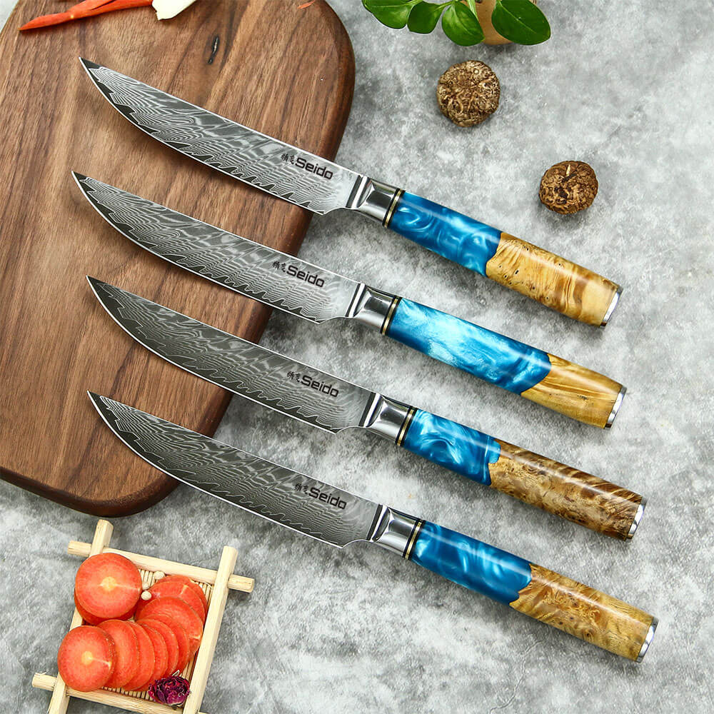 A set of nonserrated VG10 steel steak knives, featuring four knives with vibrant blue resin and wood handles, resting on a cutting board.