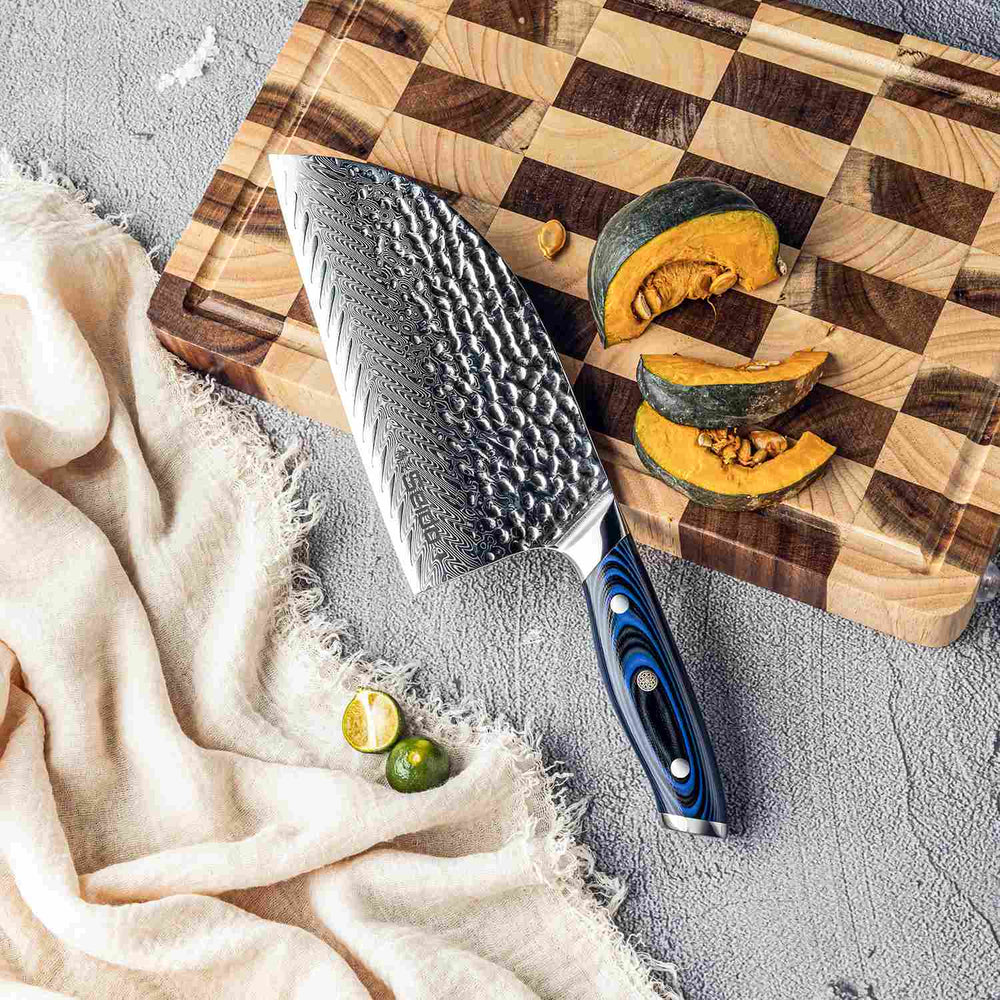 Kanpeki Cleaver knife with a G10 blue handle on a wooden cutting board with sliced squash and limes.