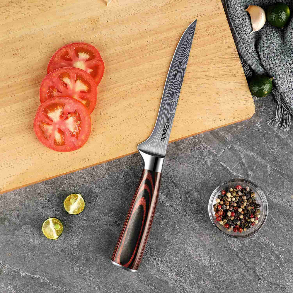 Knife with a decorative handle on a cutting board with sliced tomatoes and spices.