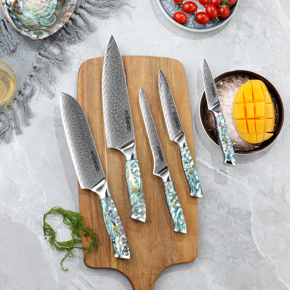 Awabi Series, 5-piece Damascus Steel Chef Knives paying on a cutting board along side fruits.
