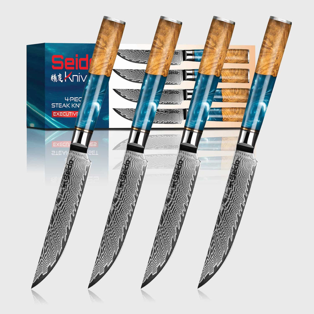 Set of 4 executive series Damascus steel steak knives with wooden handles in front of a seido knives box.