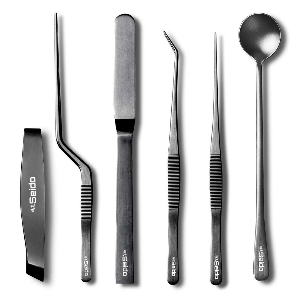 A close-up of the ribbed, non-slip 6-piece black and silver plating tweezer tool set, on a white background.