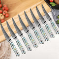 Set of 8 serrated awabi steak knives by seido knives, with decorative abalone handles on a wooden cutting board.