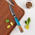 Knife with a blue handle on a wooden cutting board with limes and mint leaves.