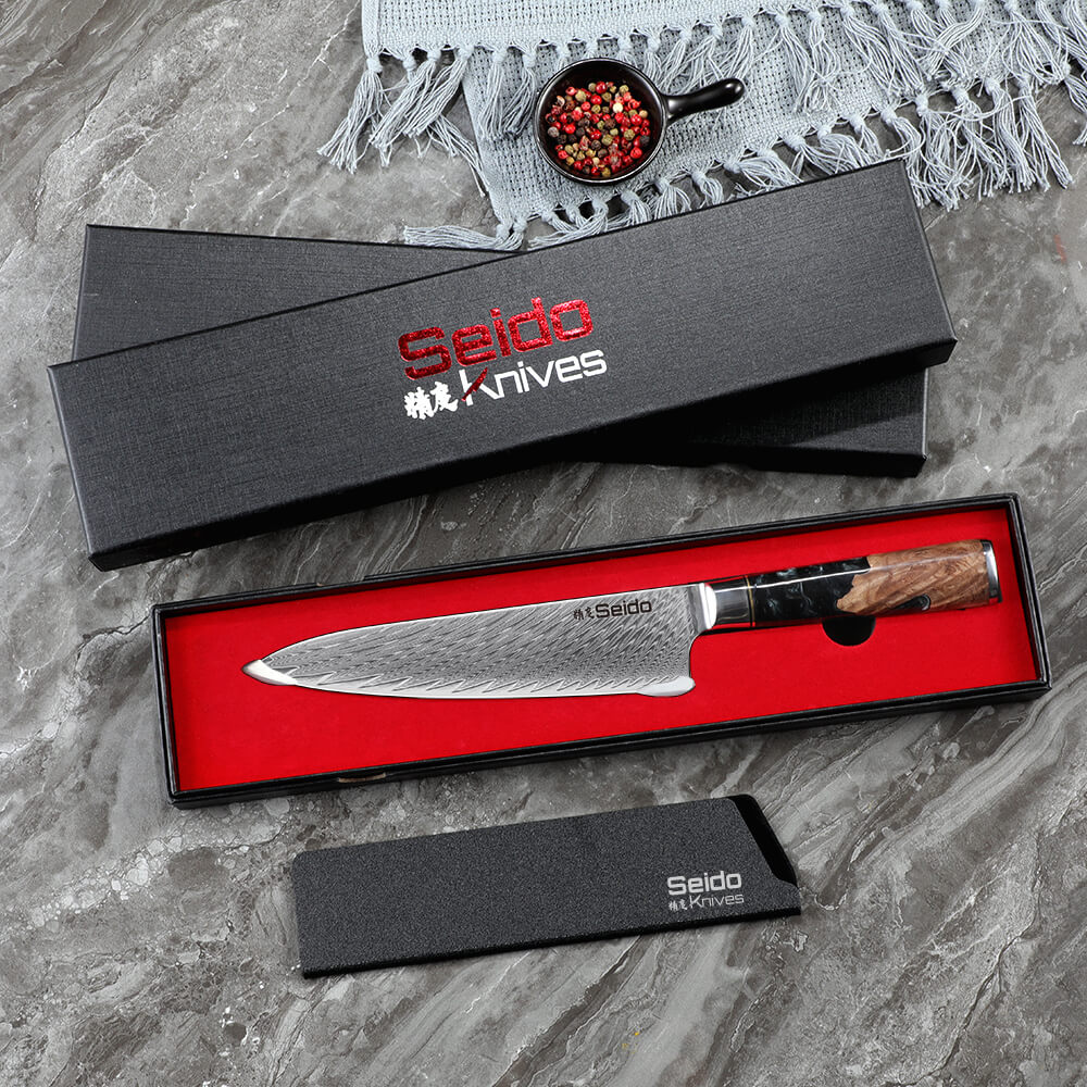  A table with a knife and a gift box, including the Black Executive Gyuto Chef Knife by Seido Knives.