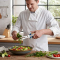Man in a kitchen preparing a salad, cutting fresh herbs with the executive serires shears
