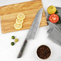 
A sharp Katsuryoku Gyuto Chef Knife from Seido Knives laying on a cutting board near fresh vegetables.