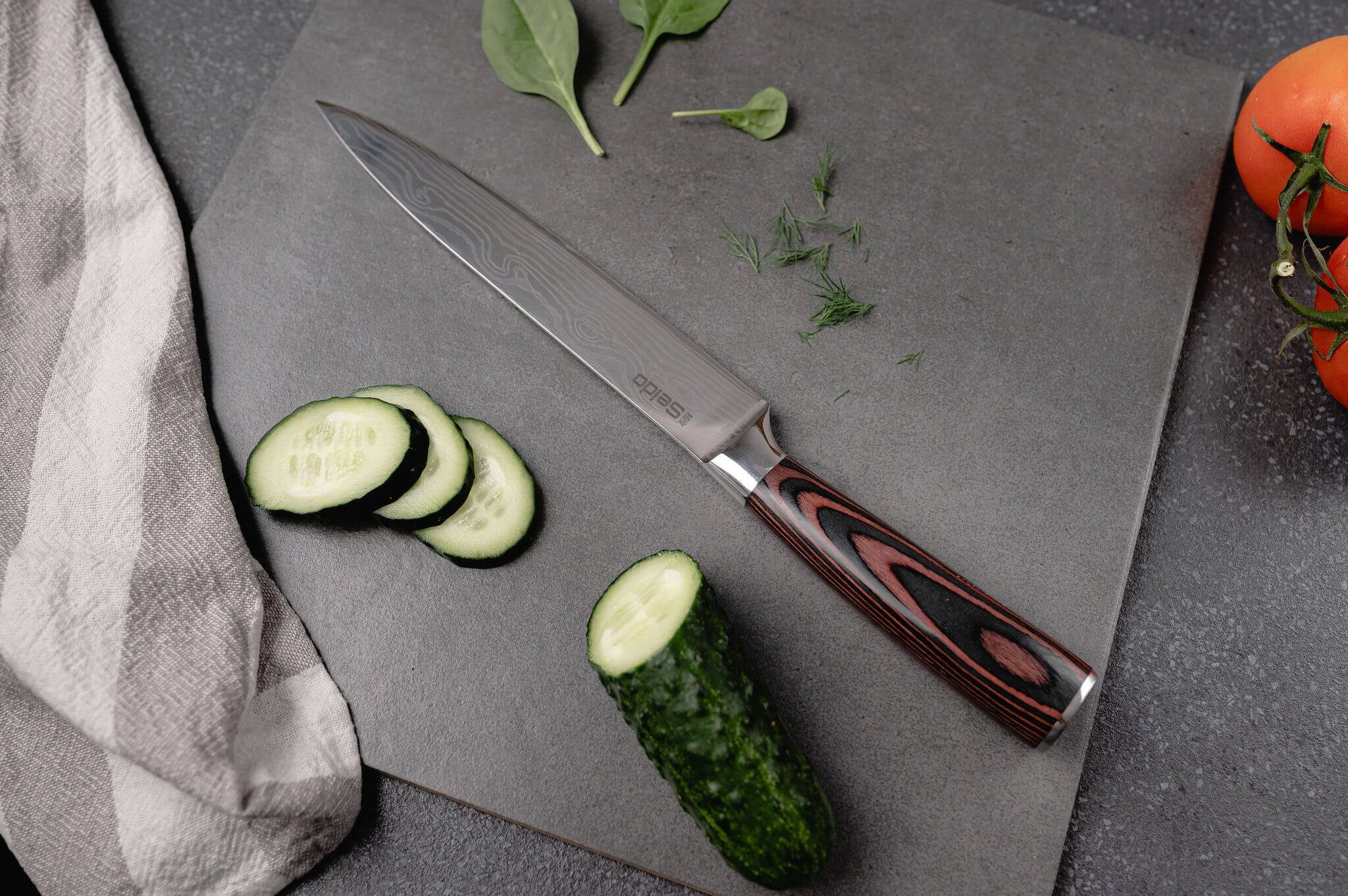 A Seido knife and fresh cucumbers on a cutting board, ready for slicing and dicing!