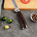 Knife with a wooden handle on a gray surface with limes and a cutting board in the background