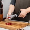 Person using kitchen shears and cutting chili peppers on cutting board