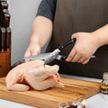 Person cutting a chicken with kitchen shears on a wooden cutting board.