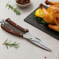 Butcher's shears on a table with a roasted chicken, lemon, and rosemary.