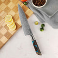 Chef's knife with a decorative handle on a cutting board with lemons and limes.