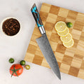 Chef's knife with a decorative handle on a wooden cutting board with sliced lemons and vegetables.