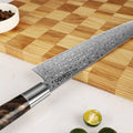 Shinko Series 8.5 inch Kiritsuke knife on a wooden cutting board with limes and a bowl of spices.