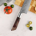 Shinko Santoku stabilized maple and resin handle detail, on a cutting board with vegetables.