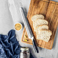Shujin Series 10-inch serrated Damascus bread knife on a wooden cutting board with sliced bread.