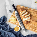 Knife with textured blade on a wooden cutting board with sliced bread and lemon slices.