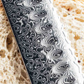 Close-up of a knife blade with a unique pattern on a textured surface