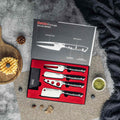 Set of 4 charcuteries knives in a seido packaged box, on a textured surface with waffles and herbs.