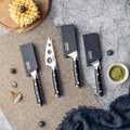 Set of 4 cheese knives with black handles, secured in a sheath on a textured surface with food items.