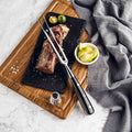 Shujin meat carving fork, on a wooden cutting board with a salt shaker and lime wedges, on a marble surface.