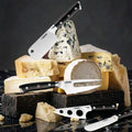 Set of charcuterie & cheese knives on a wooden board with various types of cheese.