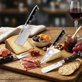 Charcuterie set on a wooden cutting board with cheese, meats, and crackers alongside cheese knives and a glass of red wine.