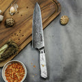A Takoizu Gyuto Chef Knife from Seido Knives rests on a cutting board, surrounded by aromatic spices and fresh herbs.