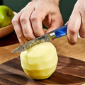 Person cutting an apple with a paring knife on a wooden surface