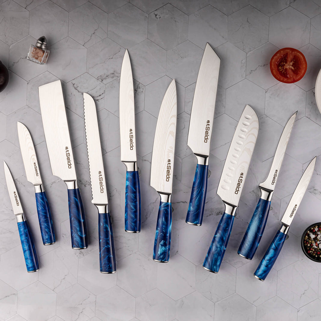 Behold the Tengoku Chef Knife Set from Seido Knives! A collection of knives with blue handles, arranged on a counter.