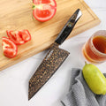 Kurogane 7-inch Bunka knife with rainbow Damascus blade beside fresh vegetables on a cutting board