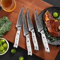 Four Takoizu serrated steak knives beside a plated steak
