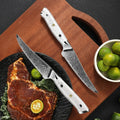 Two Takoizu serrated steak knives beside a plated steak